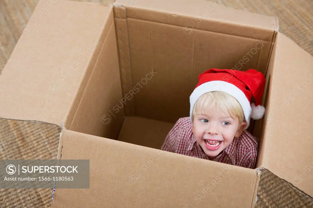 Four year old boy playing in a cardboard box