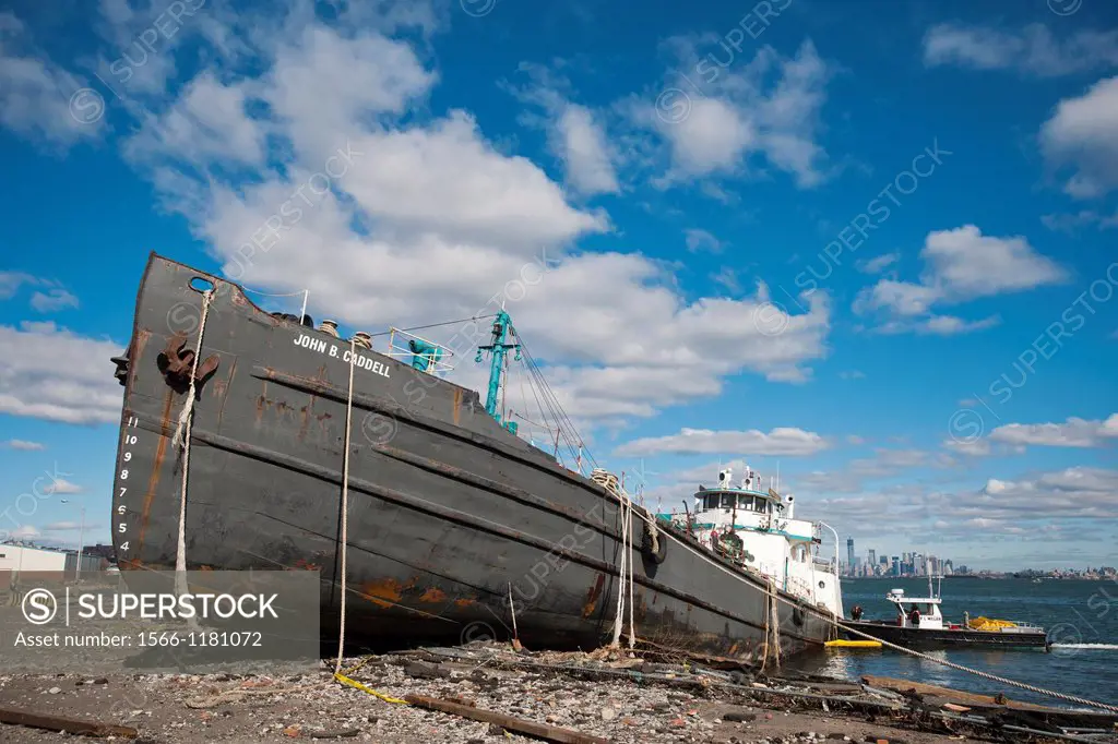 Workers install a boom to collect any leaking fuel on the John B Caddell, a 168 foot, 700 ton water tanker, seen grounded on the shore of the Stapleto...