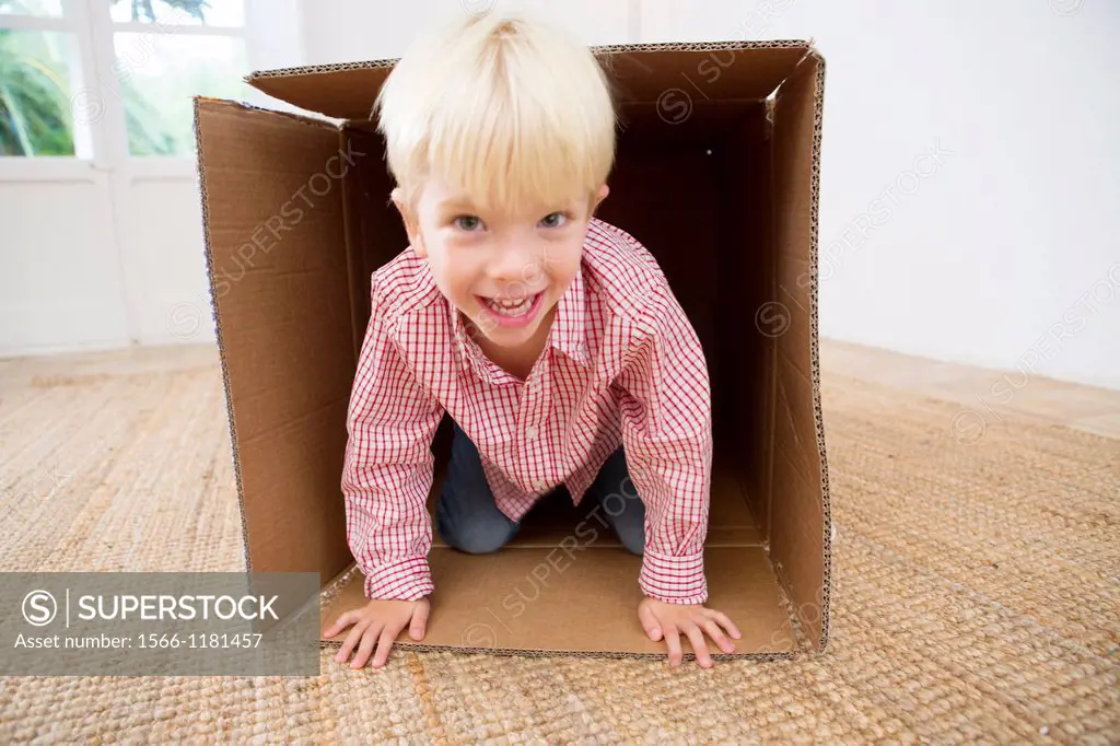 Four year old boy playing in a cardboard box