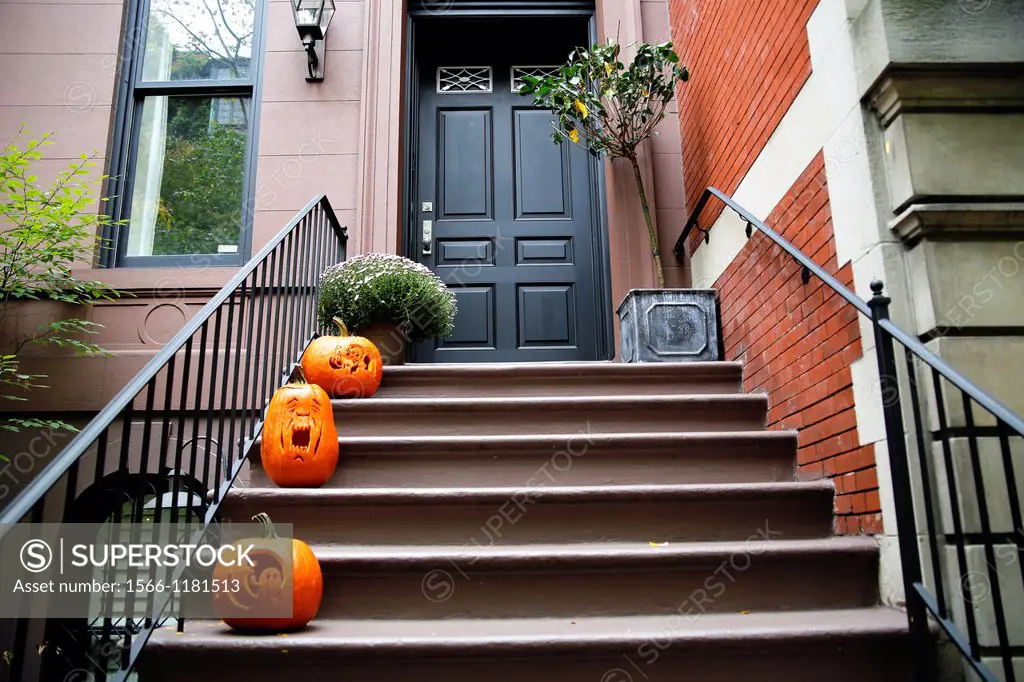 Three Halloween Carved Pumpkins Jack-O-Lanterns on the Front Steps of a NYC Brownstone Town House