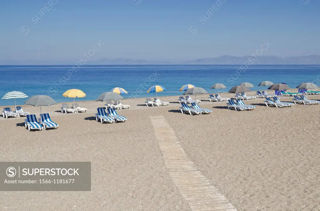 Sunloungers with beach umbrellas on an empty Greek beach on Rhodes Island, Greece