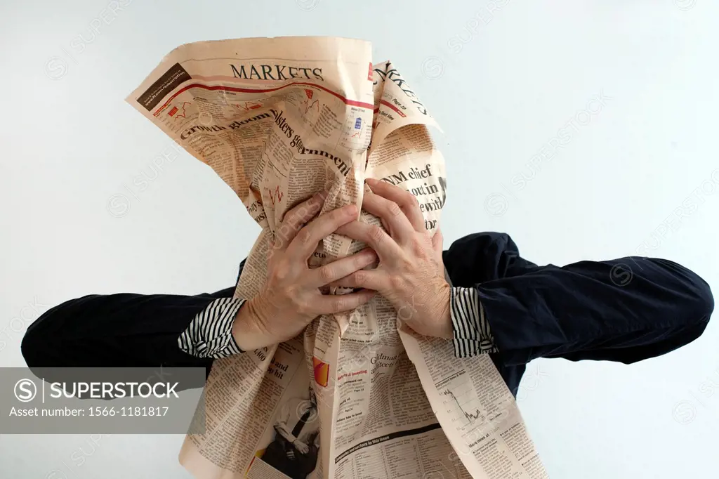 Mature woman covering her face with financial newspaper.