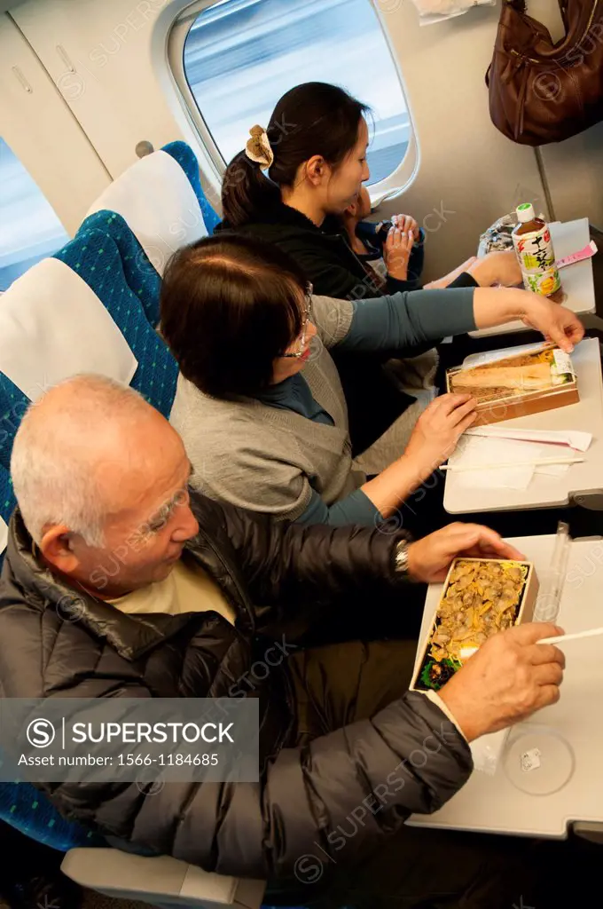 Japanese train travellers dining on the traditional o-bento packed lunches aboard a Shinkansen or Bullet Train