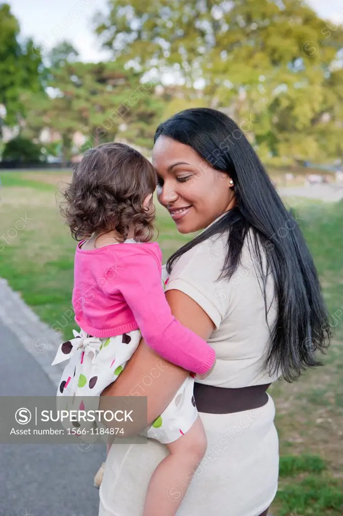Portrait of young latino mother and daughter looking at each other in park