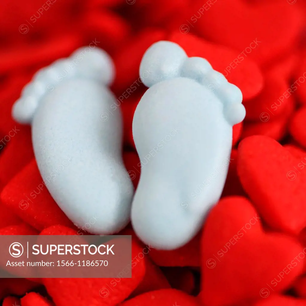 candy blue baby feet in a bed of red hearts, conceptual and fun new baby boy