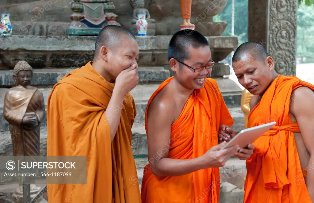 Cambodia, Siem Reap, Young monks laughing and playing at digital tablet