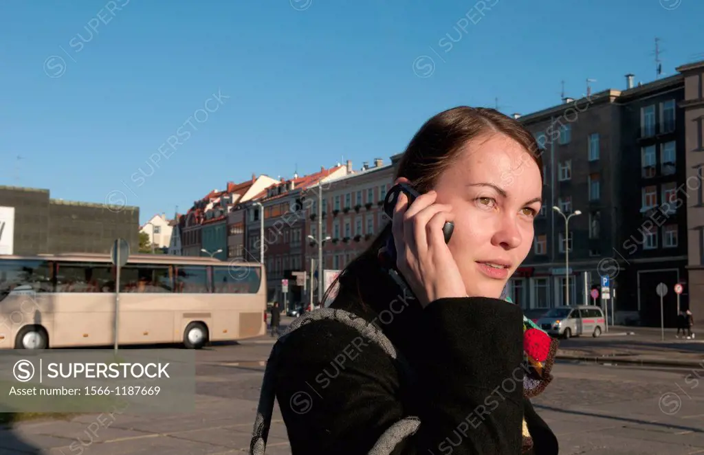 Riga Latvia modern woman on cell phone in downtown capital statue with scarf
