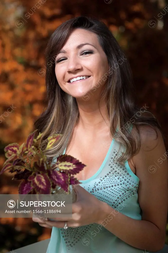 Portrait of a 21 year old woman outdoors holding a jar with a coleus cutting