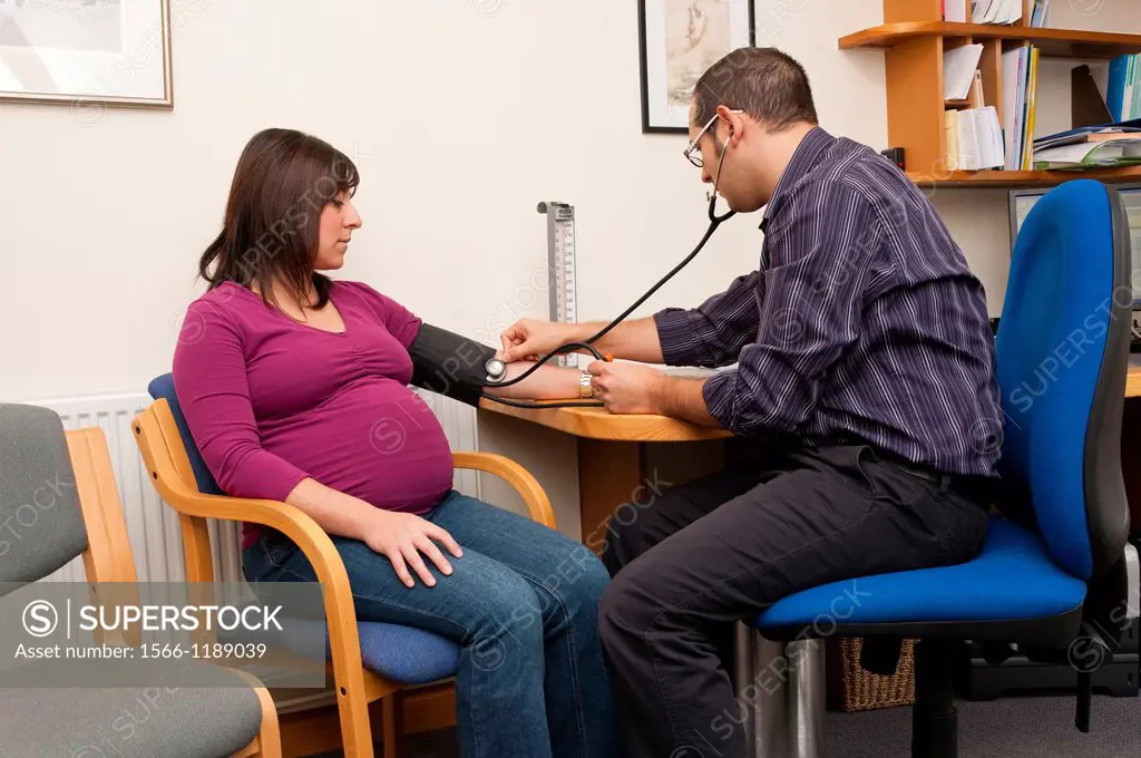 GP Doctor checking pregnant woman blood pressure