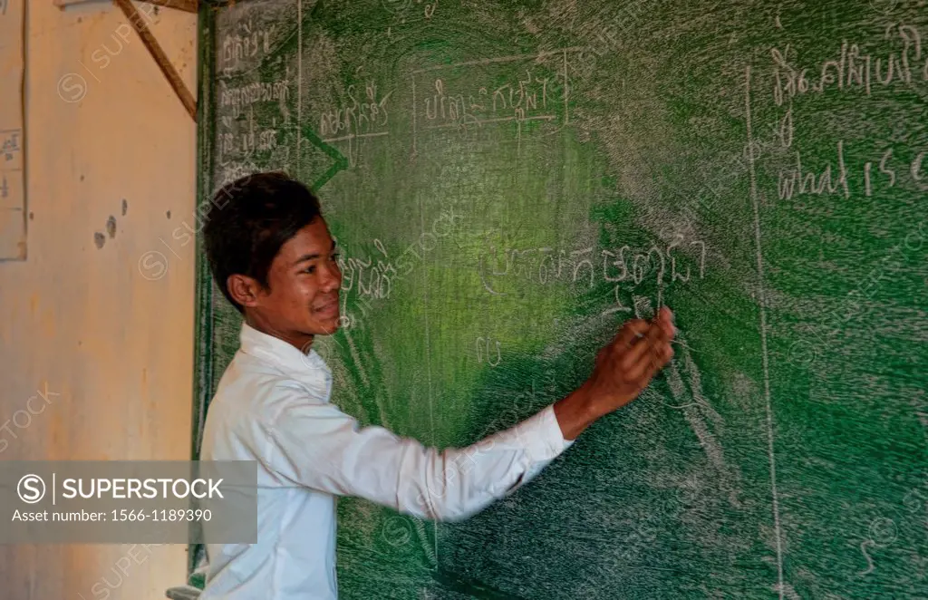 School boy inschool grade 8 writing on board near Siem Reap In Cambodia Asia