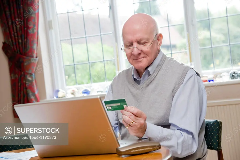 Mature Man confidently and securely paying his bills online with a credit card