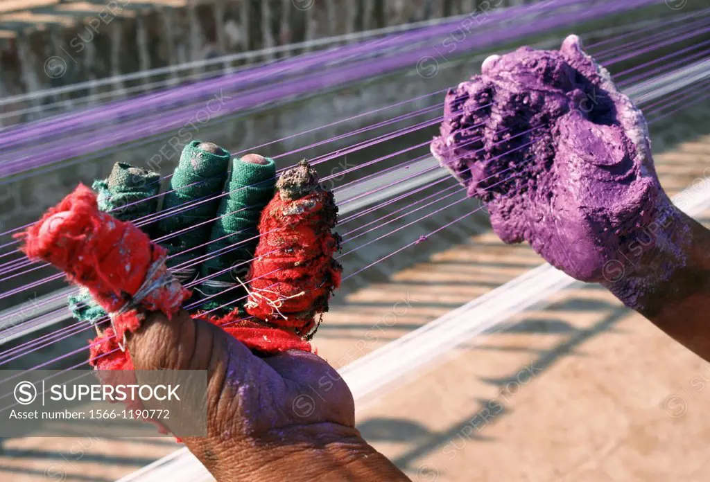 Hands of a man dying strings of kites before the kite flying festival held every spring in Pakistan. Colours are mixed with pieces of glass to strengh...