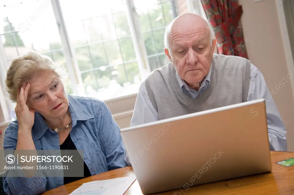 Mature couple using a laptop computer, worrying about their bills and debts