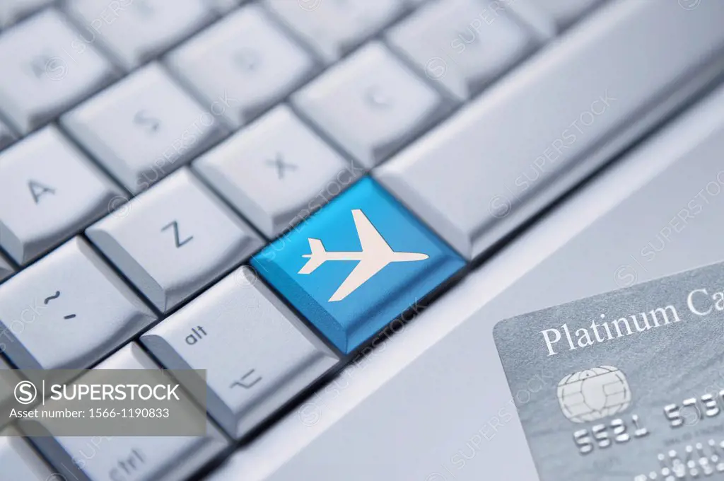 Detail of a laptop keyboard with one blue key with an aeroplane symbol on it and a credit card at the bottom right corner