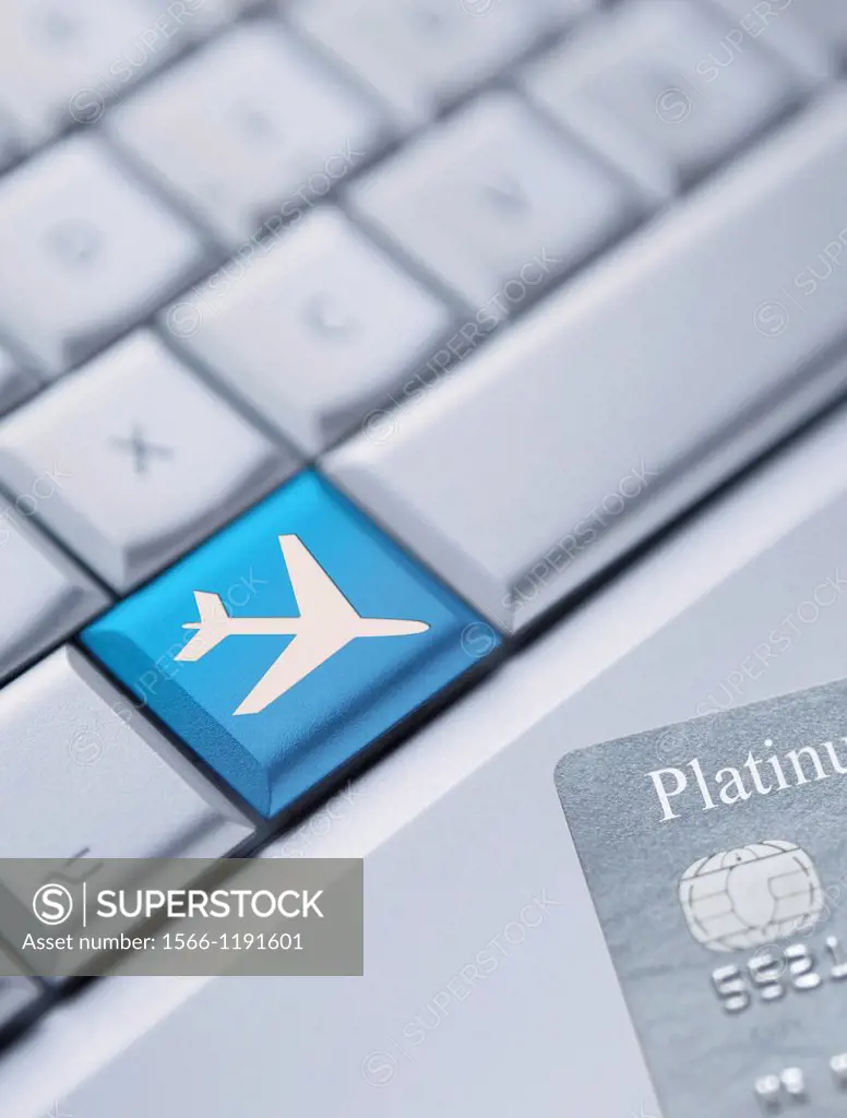 Detail of a laptop keyboard with one blue key with an plane symbol on it and a credit card at the bottom right corner