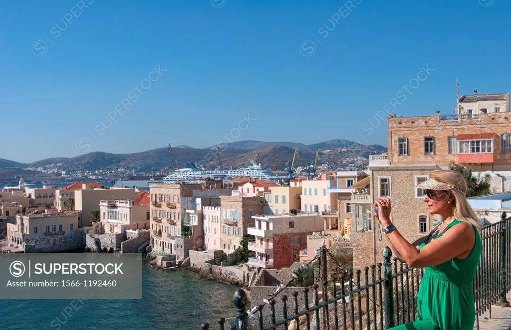 Syros Greece Islands a woman tourist camera in Hermoupolis capital with white buildings water ocean and classic architecture