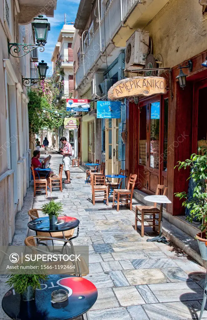 Overhanging plants quaint street in downtown area of capital of Syros called Hermoupolis with shops and stores and cafes