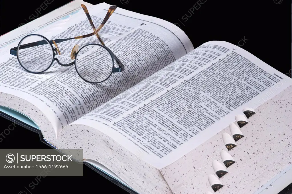 A pair of spectacles lies on the pages of an open dictionary