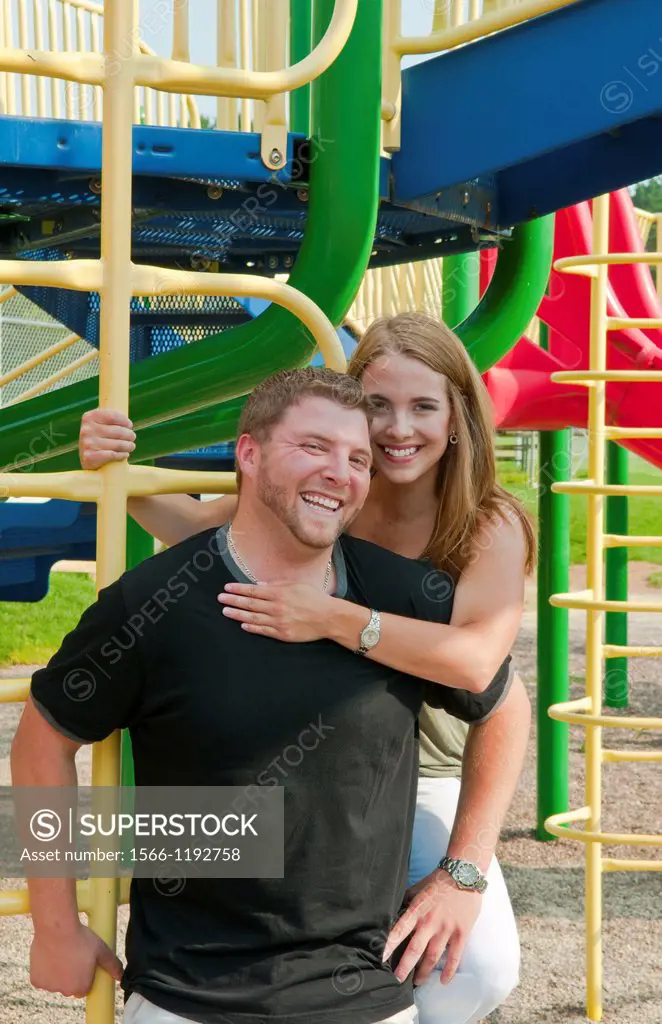 Midwest couple aged 22 playing and dating in park at monkey bars and hugging playing