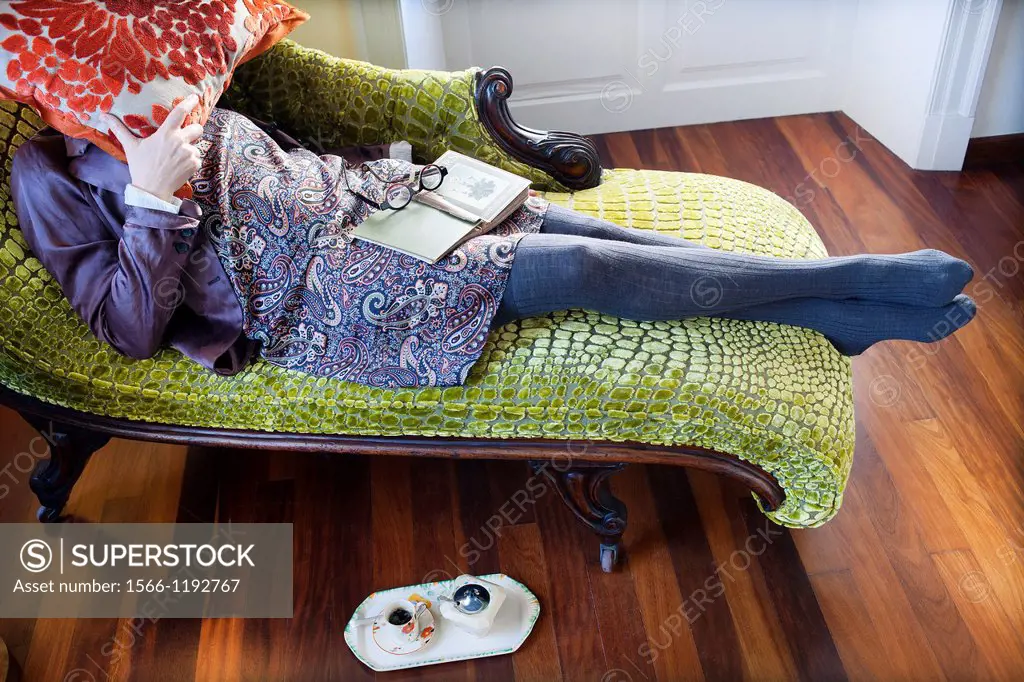 Woman with a pillow covering her face lying on a chaise longue