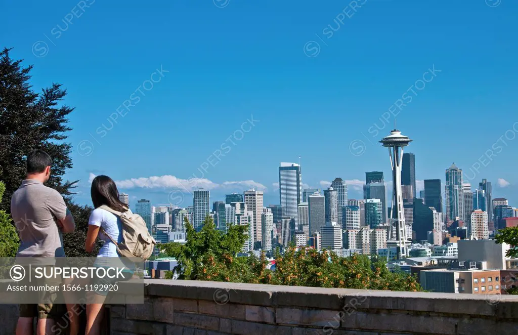 Seattle, Washington skyline from Queen Anne´s Hill with couple taking photos and Mt Rainier visable in background
