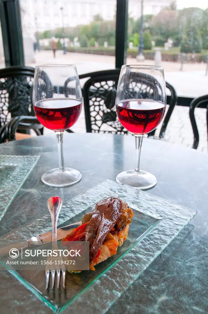Spanish appetizer: two glasses of rose wine with tapa of anchovy fillet with red pepper. Oriente Square, Madrid, Spain.