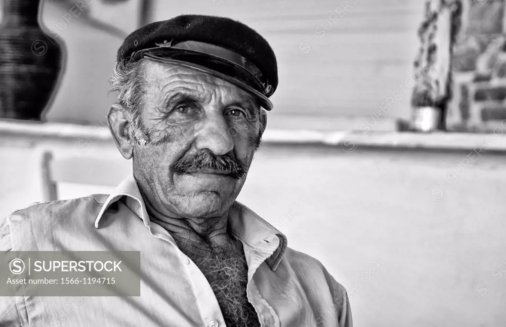 Local man portrait with Greek hat at restuarant in white in Mykonos in Greek Islands in Greece Europe