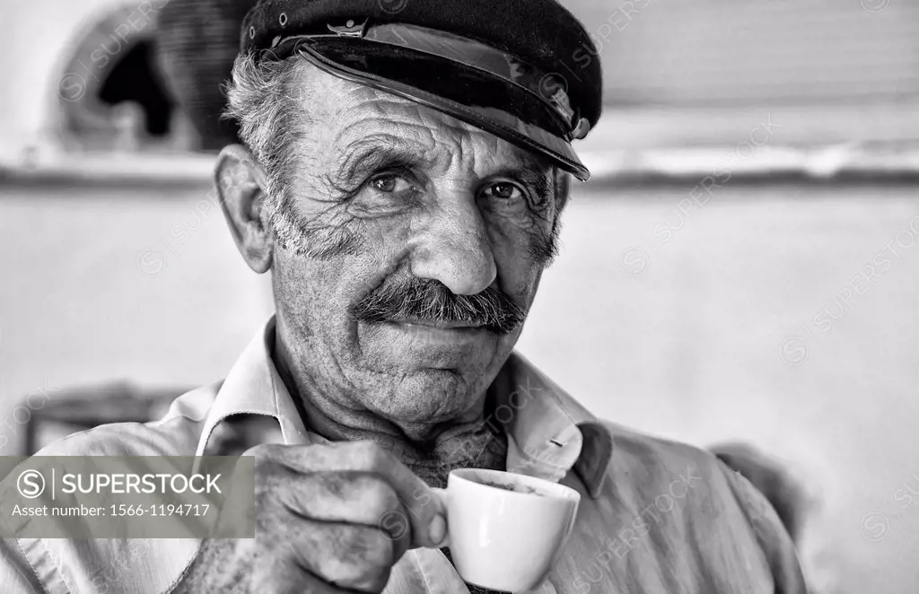 Local man portrait with Greek coffee with Greek hat at restuarant in white in Mykonos in Greek Islands in Greece Europe