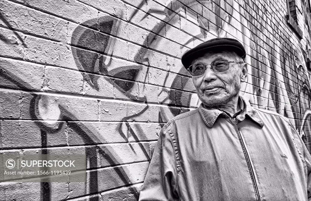 Old Chinese man with wall mural in Chinatown San Francisco California
