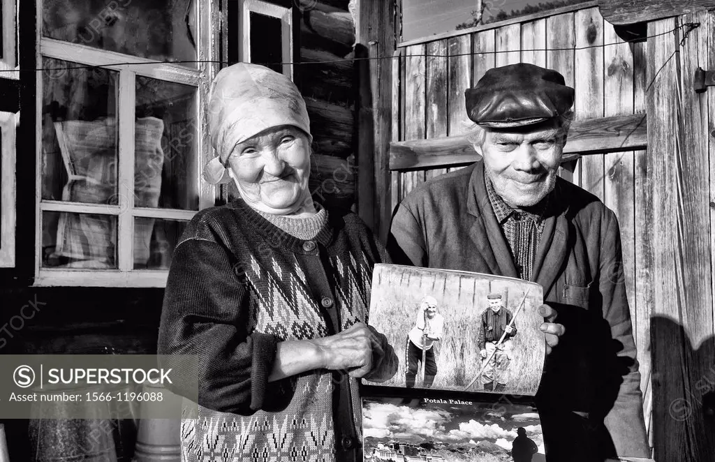 Poor farmers at home in simple clothes portrait seeing portrait of themselves in book in Listvyanka near Irkutsk in Siberia Russia