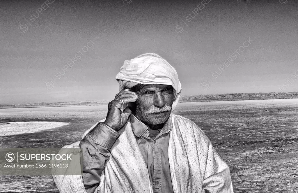 Arab man on cell phone Great Dry Salt Lake Chott el Jerid in Sahara Desert sand near Douz in Tunisia isolated Africa
