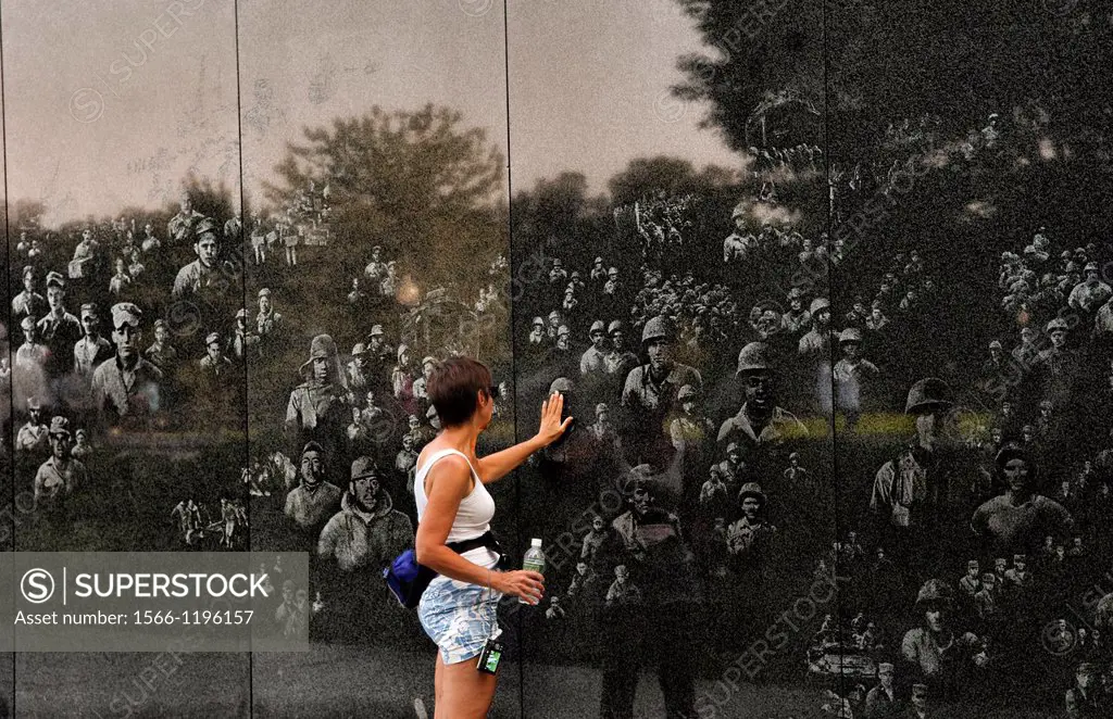 Woman looking at faces and reflections in wall in of platoon at new Korean War Veterans Memorial in Mall in Washington DC in USA