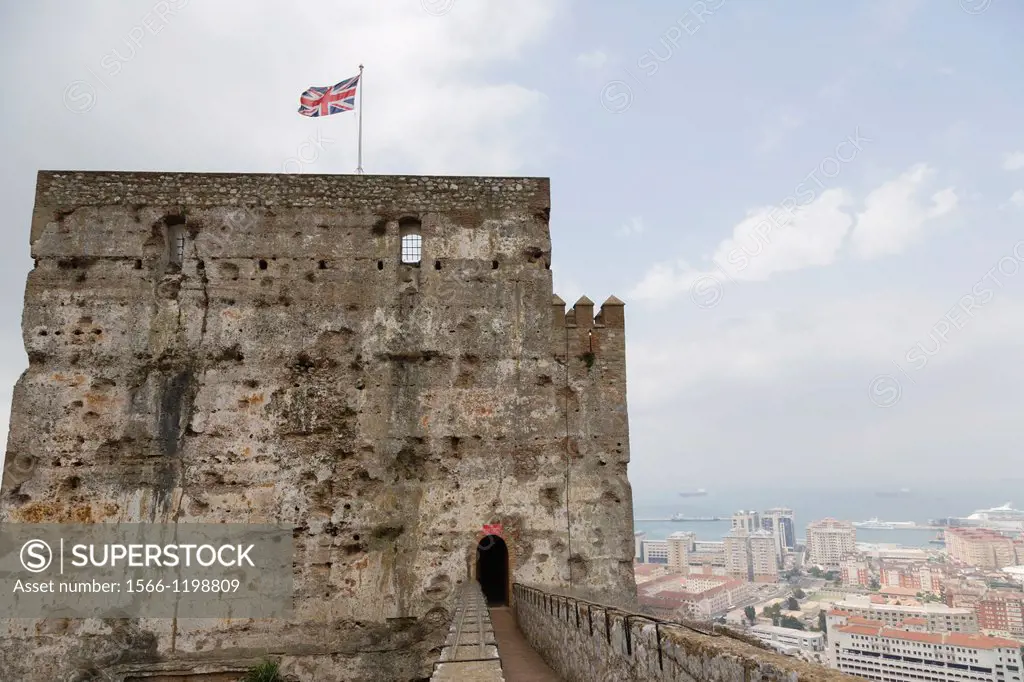 The Tower of Homage of The Moorish Castle with flying Union Flag against Gibraltar with its harbour and Bay of Gibraltar from Upper Rock Nature Reserv...