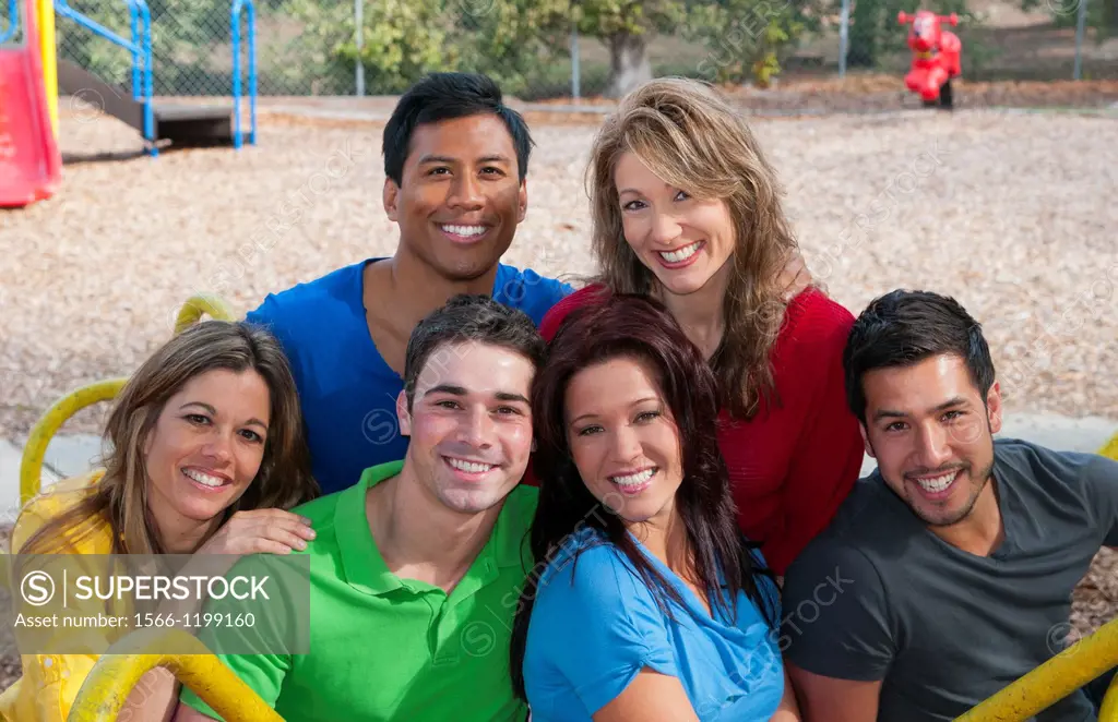 Multi ethnic friends aged 20s in playground laughing and sharing fun in spinning wheel of colors together