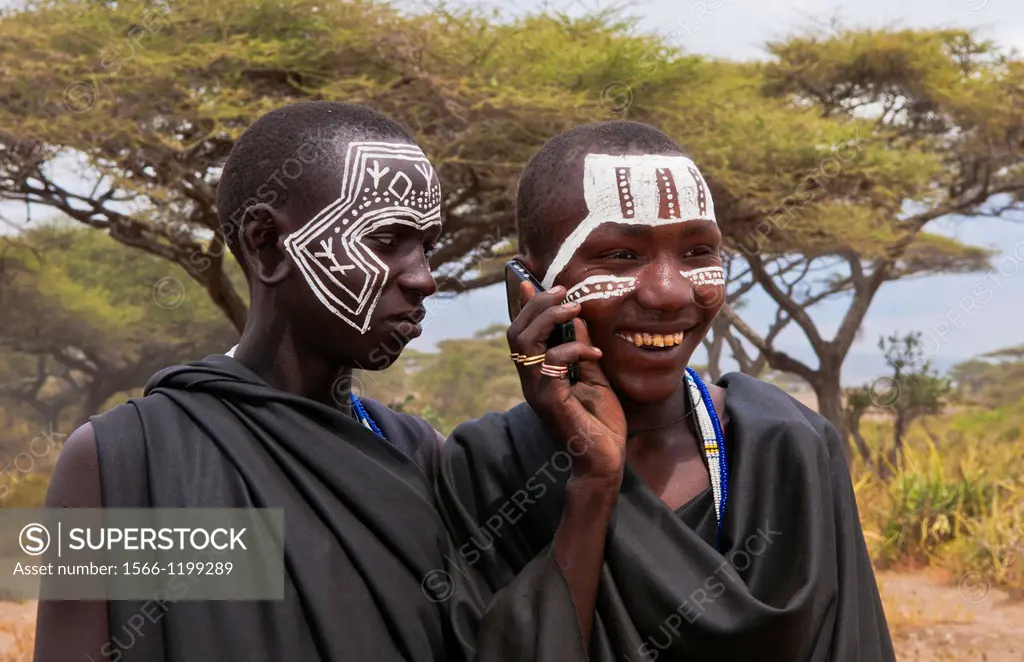 Tanzania Serengeti Africa Masai Maasai boys talking on cell phone in black clothes from circumcision ceremony with face paint 7