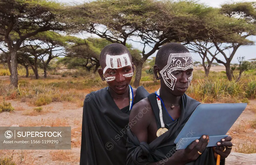 Tanzania Serengeti Africa Masai Maasai boys playing with Digital tablet computer in black clothes from circumcision ceremony with face paint 7