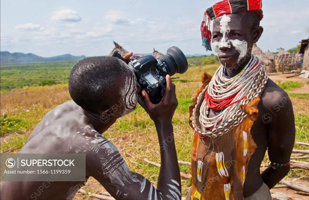 Korcho Ethiopia Africa village Lower Omo Valley Karo tribe with painted faces with boy using modern camera taking photos 25