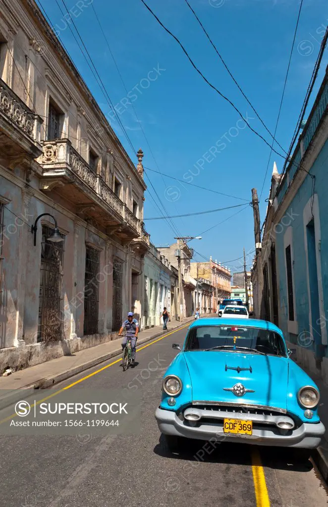 Camaquey Cuba street scene of old Oldsmobile car on street and buildings