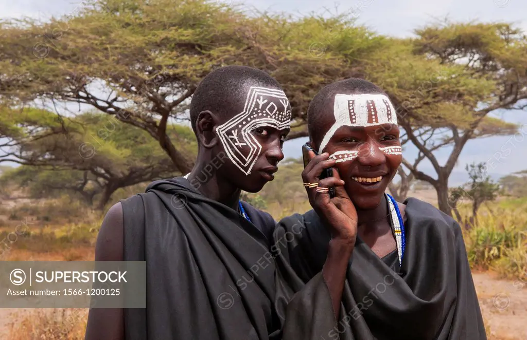 Tanzania Serengeti Africa Masai Maasai boys talking on cell phone in black clothes from circumcision ceremony with face paint 7