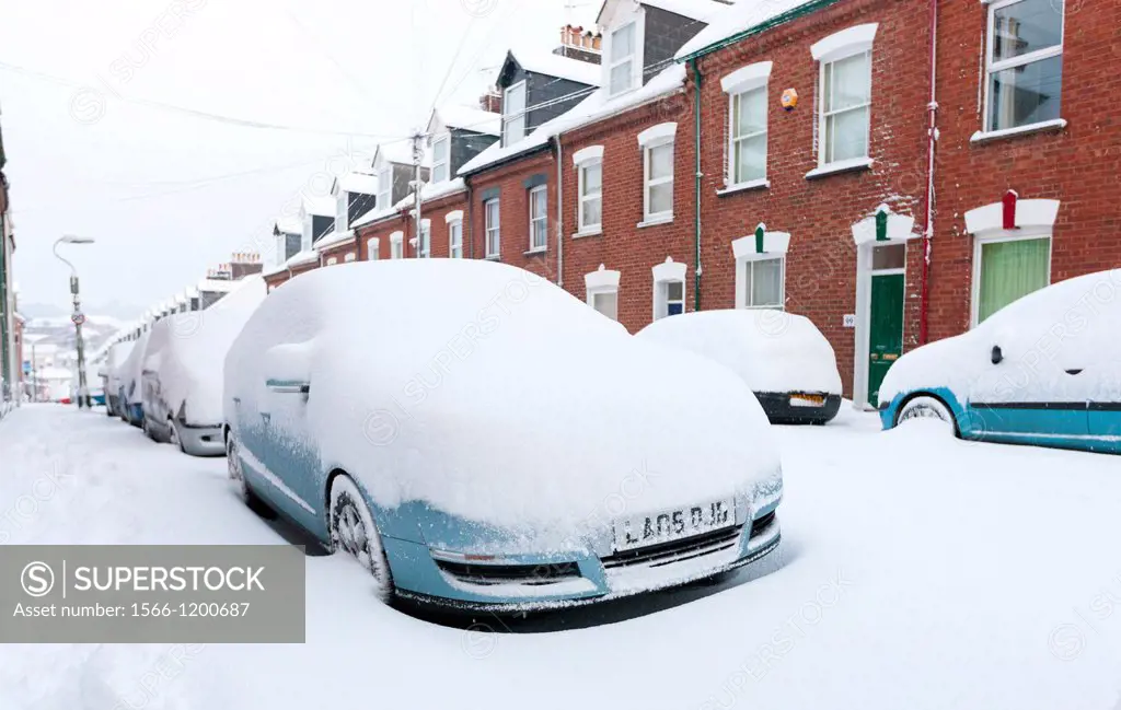 A row of snow covered cars parked along a street in Exeter, Devon, England, UK, Europe