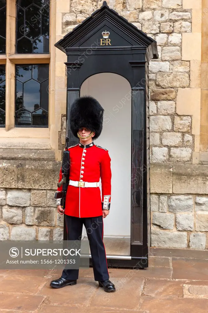 A guard wearing a traditional bearskin stands guard outside the Jewel House in the Tower of London, London, England.