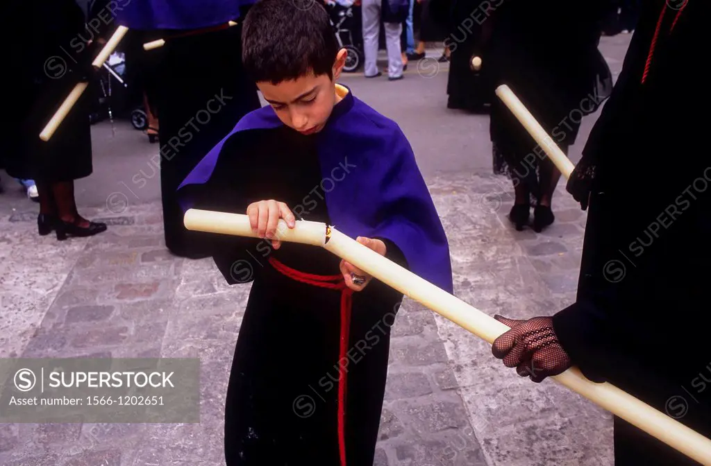 young penitent lighting the candle  Good Friday procession in Calle Carniceria  Brotherhood of `Soledad Campo Principe´  Granada  Andalusia, Spain