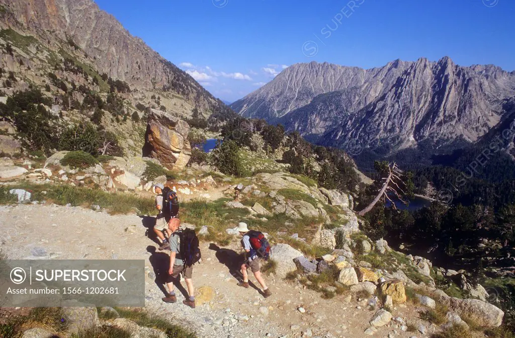 Hikers climb to the Amitges refuge, in background at right Encantats mountains, Aigüestortes i Estany de Sant Maurici National Park,Pyrenees, Lleida p...