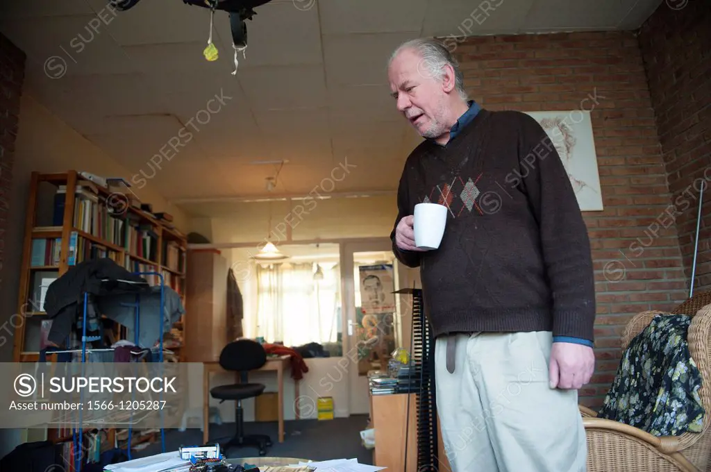 Rotterdam, Netherlands. Older man in his disorganized living-room.
