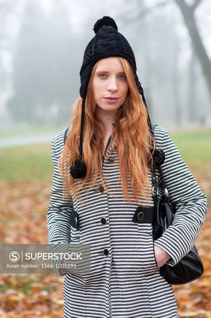 Breda, Netherlands. Young, fashionable and redheaded woman in a city-park.