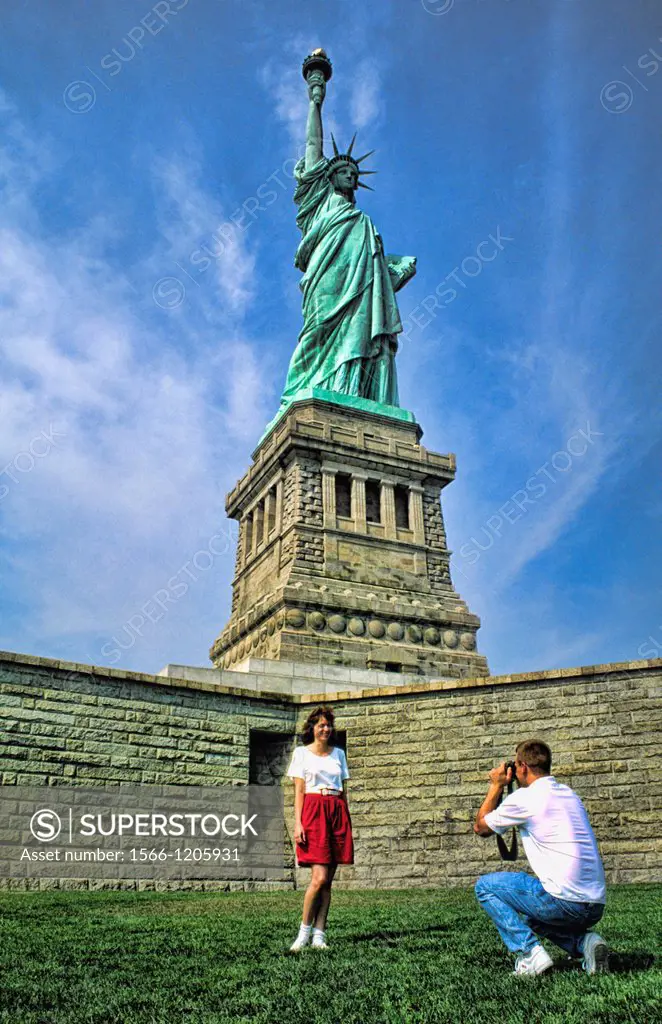A couple of torists taking photos at the beauty of the famous Statue of Liberty on Ellis Island in New York City USA