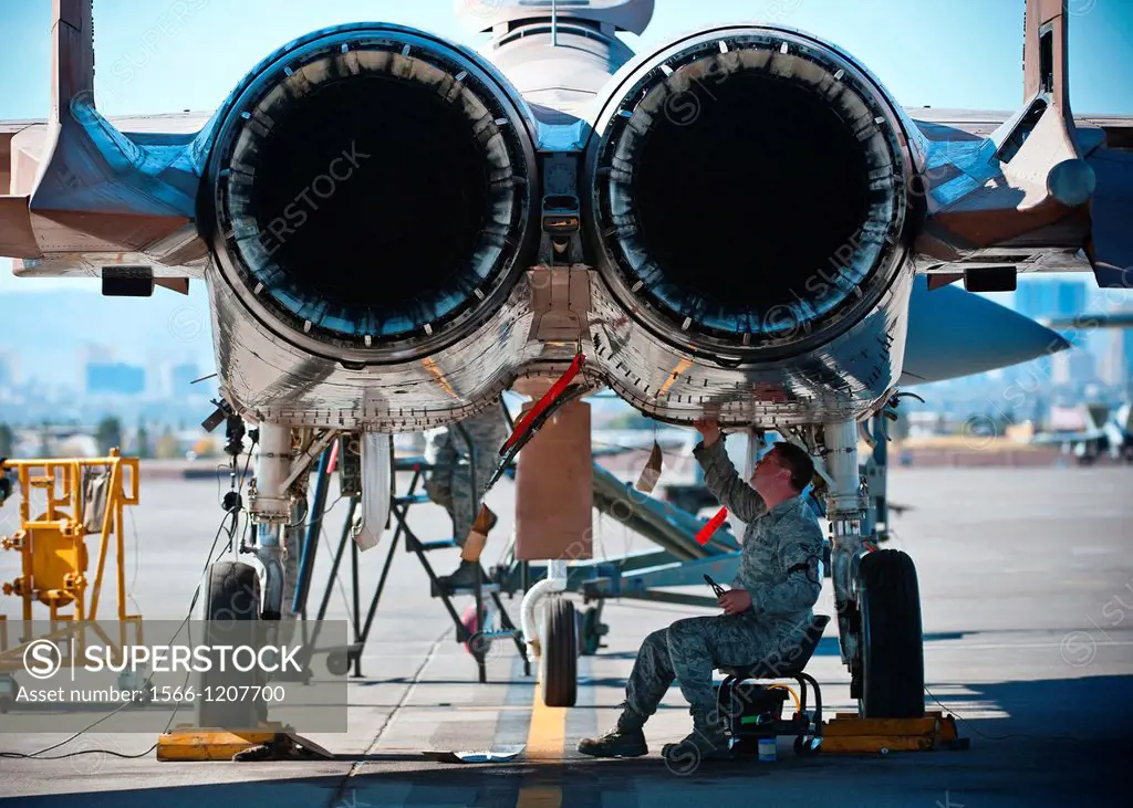 Airman 1st Class Bill Bossinger tightens wiring underneath an F-15 Eagle during the mission employment phase exercise at Nellis Air Force Base, Nev , ...