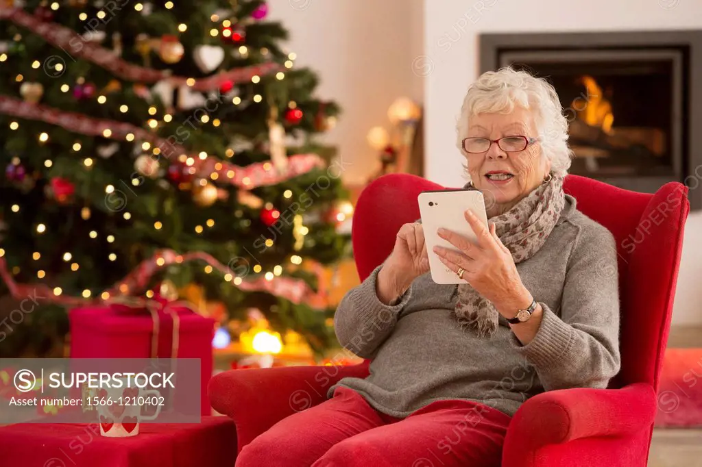 Senior woman communicating with family on her tablet computer at Christmas time