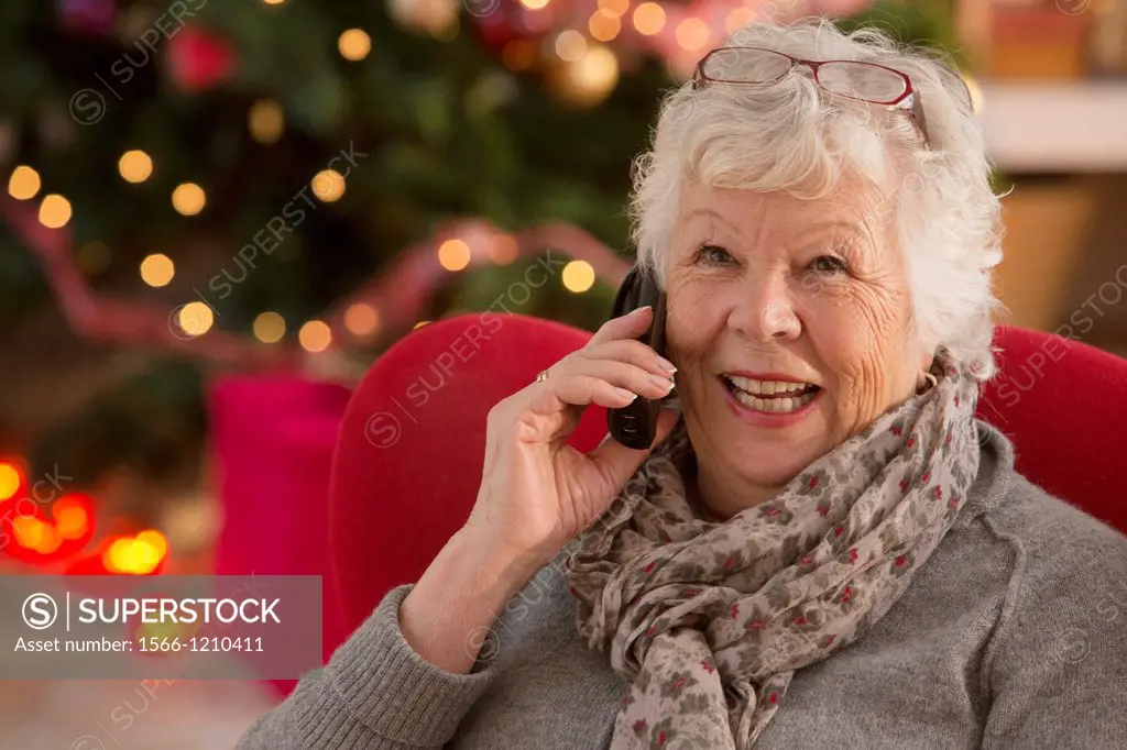 Senior woman communicating with family on her home phone at Christmas time