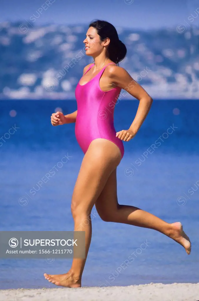 Pregnant woman jogging on beach